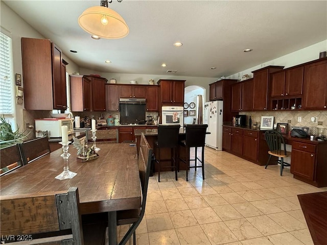 11457 Steponia Bay St, Las Vegas, NV 89141 - kitchen featuring white appliances, under cabinet range hood, backsplash, arched walkways, and recessed lighting