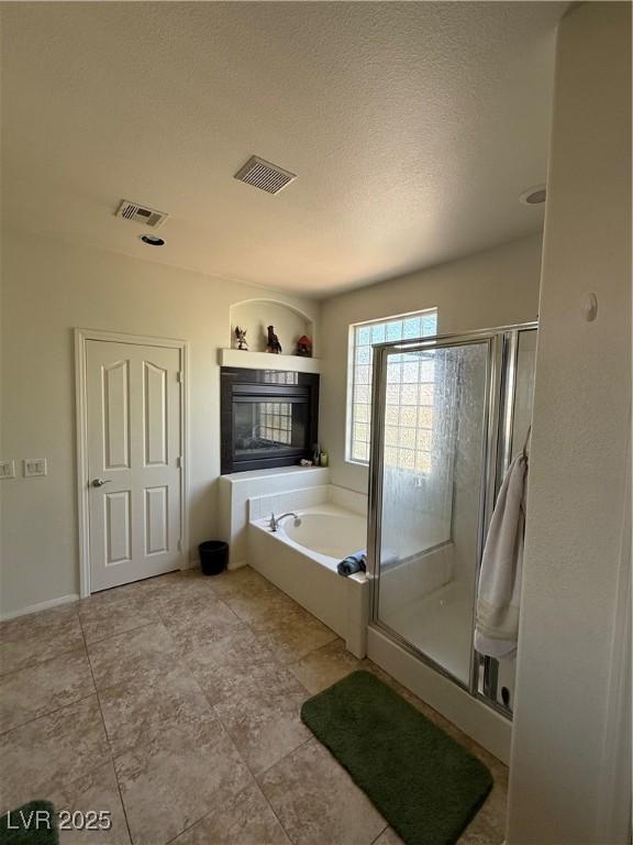 11457 Steponia Bay St, Las Vegas, NV 89141 - bathroom featuring a stall shower, a garden tub, a fireplace, and a textured ceiling