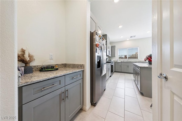 1885 Vass Springs Pl, North Las Vegas, NV 89084 - kitchen featuring appliances with stainless steel finishes, gray cabinets, light tile patterned flooring, light stone countertops, and recessed lighting