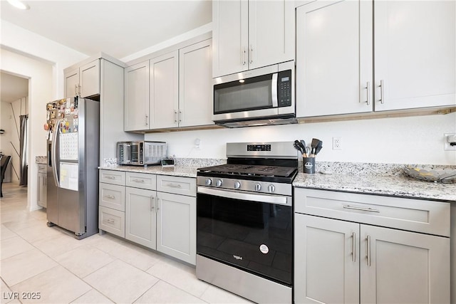 1885 Vass Springs Pl, North Las Vegas, NV 89084 - kitchen with appliances with stainless steel finishes, light tile patterned floors, light stone countertops, and gray cabinetry