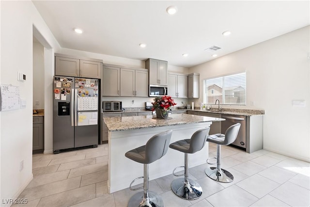 1885 Vass Springs Pl, North Las Vegas, NV 89084 - kitchen featuring appliances with stainless steel finishes, gray cabinets, a breakfast bar area, a center island, and recessed lighting