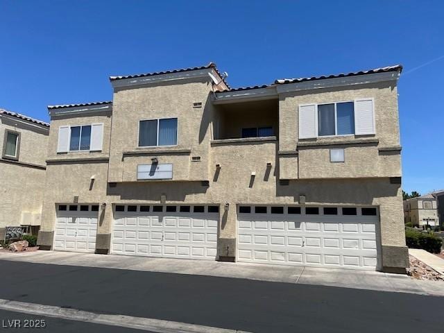 6170 E Sahara Ave Unit 1012, Las Vegas, NV 89142 - rear view of property featuring a garage, stucco siding, a tile roof, and driveway
