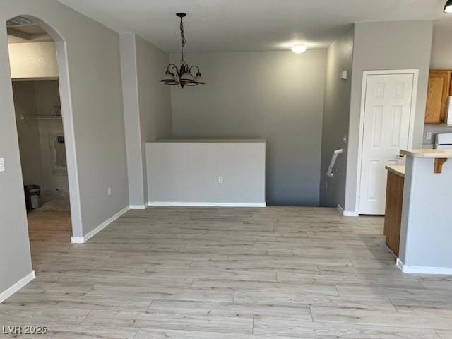 6170 E Sahara Ave Unit 1012, Las Vegas, NV 89142 - unfurnished dining area with arched walkways, light wood-type flooring, baseboards, and a chandelier