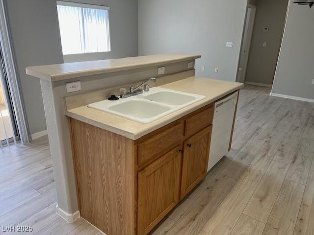 6170 E Sahara Ave Unit 1012, Las Vegas, NV 89142 - kitchen featuring white dishwasher, a center island with sink, a sink, light wood finished floors, and light countertops