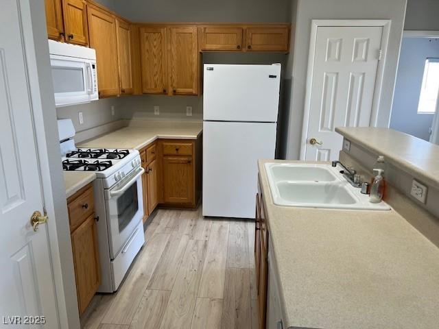 6170 E Sahara Ave Unit 1012, Las Vegas, NV 89142 - kitchen with white appliances, a sink, light wood finished floors, light countertops, and brown cabinets