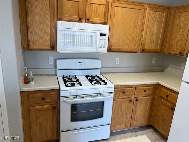 6170 E Sahara Ave Unit 1012, Las Vegas, NV 89142 - kitchen with white appliances, light countertops, and brown cabinetry