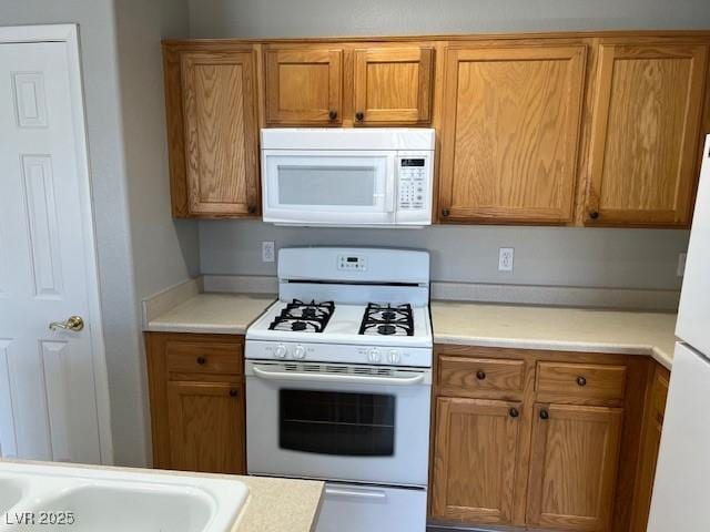 6170 E Sahara Ave Unit 1012, Las Vegas, NV 89142 - kitchen with white appliances, light countertops, and brown cabinetry