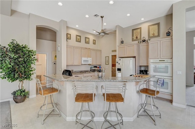 467 Beardsley Cir, Henderson, NV 89052 - kitchen featuring white appliances, arched walkways, a breakfast bar, ceiling fan, and recessed lighting