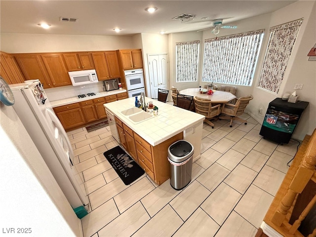 6351 Davidson Ct, Las Vegas, NV 89110 - kitchen with a sink, white appliances, tile countertops, brown cabinetry, and a ceiling fan