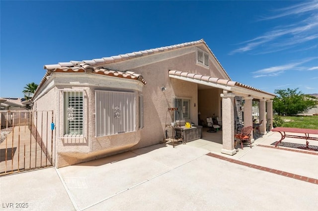 1017 Guided Dancer Ave, Henderson, NV 89015 - back of house with stucco siding, a patio area, a tiled roof, and a gate