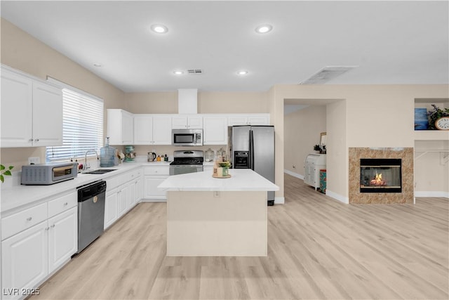 11074 Caramel Crest Ct, Las Vegas, NV 89135 - kitchen featuring appliances with stainless steel finishes, a sink, a center island, light wood-style floors, and white cabinetry