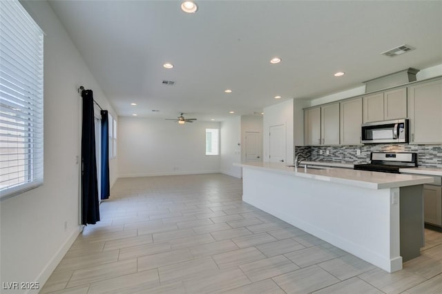 4633 Fragrant St, North Las Vegas, NV 89031 - kitchen featuring appliances with stainless steel finishes, gray cabinetry, light countertops, backsplash, and ceiling fan