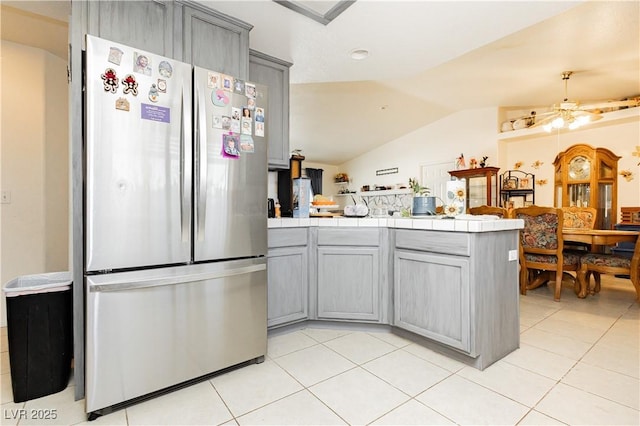 2251 Bridger St, Pahrump, NV 89048 - kitchen with freestanding refrigerator, gray cabinetry, a peninsula, tile countertops, and vaulted ceiling