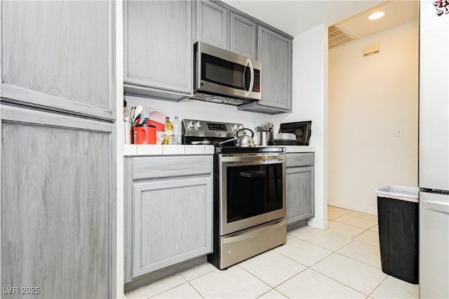 2251 Bridger St, Pahrump, NV 89048 - kitchen featuring stainless steel appliances, tile countertops, light tile patterned flooring, gray cabinets, and recessed lighting