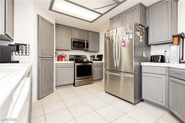 2251 Bridger St, Pahrump, NV 89048 - kitchen featuring stainless steel appliances, tile countertops, light tile patterned floors, and gray cabinetry