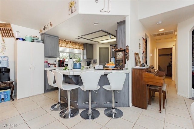 2251 Bridger St, Pahrump, NV 89048 - kitchen featuring a breakfast bar, light tile patterned floors, a peninsula, gray cabinets, and recessed lighting