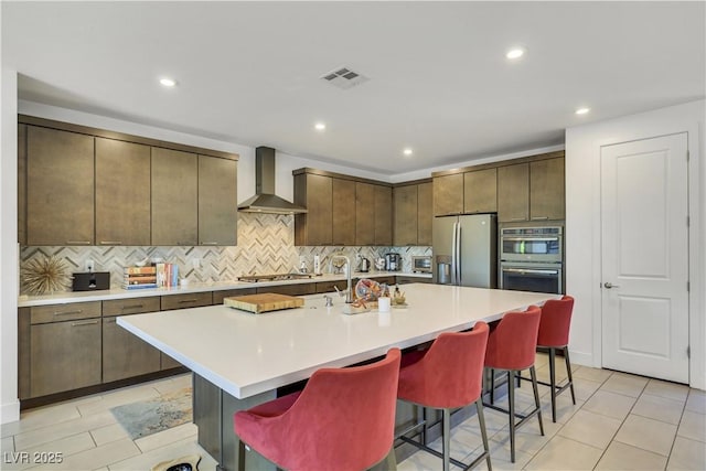 10297 Sierra Skye Ave, Las Vegas, NV 89166 - kitchen featuring wall chimney range hood, appliances with stainless steel finishes, a breakfast bar area, tasteful backsplash, and light countertops