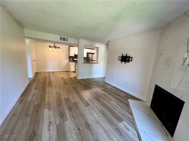 5260 Mission Monterey Ln Unit 208, Las Vegas, NV 89107 - unfurnished living room with a textured ceiling, light wood-style flooring, a fireplace, and baseboards