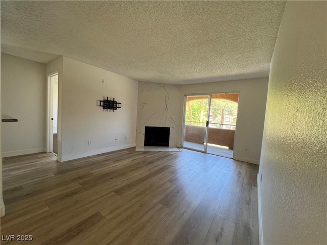 5260 Mission Monterey Ln Unit 208, Las Vegas, NV 89107 - unfurnished living room with a textured ceiling, wood finished floors, a premium fireplace, and baseboards