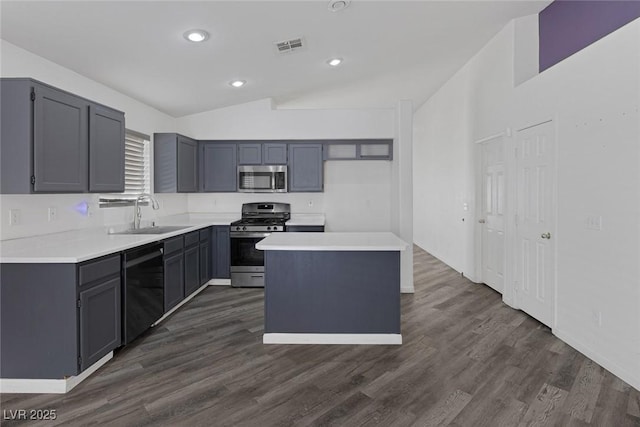 2410 Morocco Ave, North Las Vegas, NV 89031 - kitchen featuring stainless steel appliances, a sink, vaulted ceiling, dark wood finished floors, and light countertops