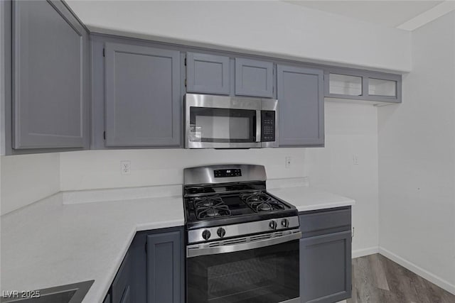 2410 Morocco Ave, North Las Vegas, NV 89031 - kitchen featuring appliances with stainless steel finishes, light countertops, wood finished floors, baseboards, and gray cabinets
