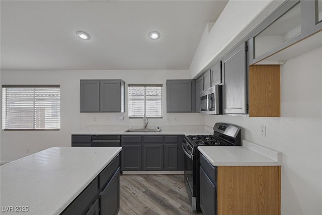 2410 Morocco Ave, North Las Vegas, NV 89031 - kitchen with stainless steel appliances, a sink, light countertops, light wood finished floors, and gray cabinetry
