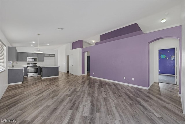 2410 Morocco Ave, North Las Vegas, NV 89031 - unfurnished living room with arched walkways, lofted ceiling, dark wood-style flooring, baseboards, and a sink
