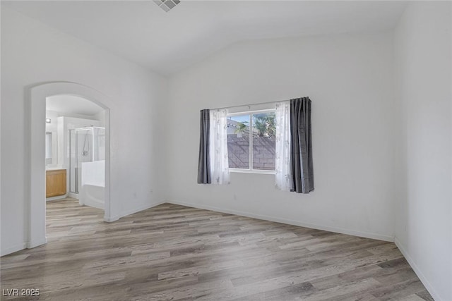 2410 Morocco Ave, North Las Vegas, NV 89031 - unfurnished room featuring arched walkways, wood finished floors, vaulted ceiling, and baseboards