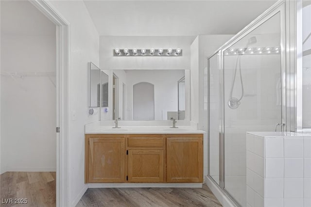 2410 Morocco Ave, North Las Vegas, NV 89031 - bathroom with wood finished floors, a shower stall, double vanity, and a spacious closet