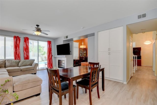 4835 Willow Glen Dr, Las Vegas, NV 89147 - dining space with a ceiling fan, light wood-type flooring, a glass covered fireplace, and baseboards