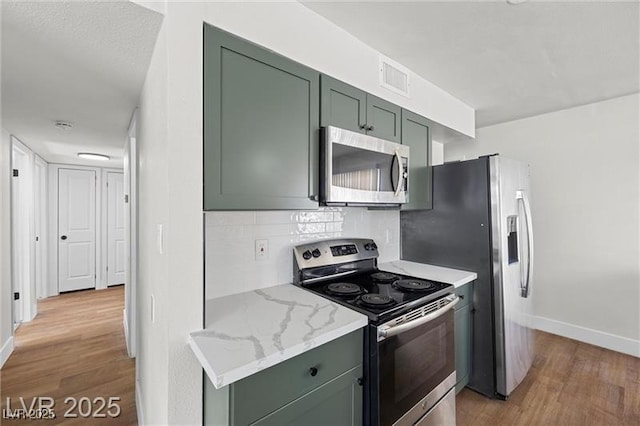 728 Carpenter Dr, Las Vegas, NV 89107 - kitchen with appliances with stainless steel finishes, green cabinetry, light wood-type flooring, baseboards, and decorative backsplash