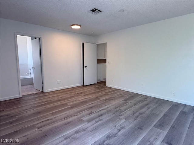 5600 Grossmont Ave, Las Vegas, NV 89110 - unfurnished bedroom with wood finished floors, a textured ceiling, baseboards, and ensuite bath