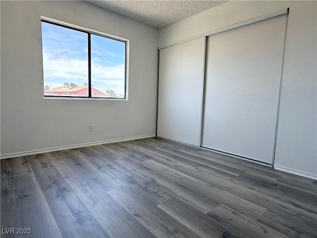 5600 Grossmont Ave, Las Vegas, NV 89110 - unfurnished bedroom with wood finished floors, a textured ceiling, a closet, and baseboards
