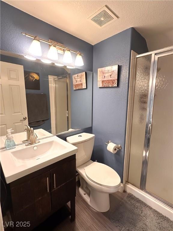 2549 Sundew Ave, Henderson, NV 89052 - full bath with a textured wall, vanity, a stall shower, toilet, and wood finished floors