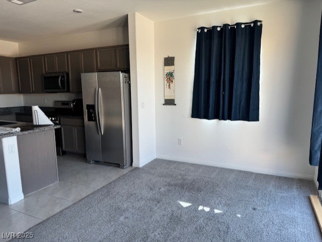 411 Hellebores Ave, North Las Vegas, NV 89084 - kitchen with stainless steel appliances, dark brown cabinets, light carpet, baseboards, and light tile patterned floors