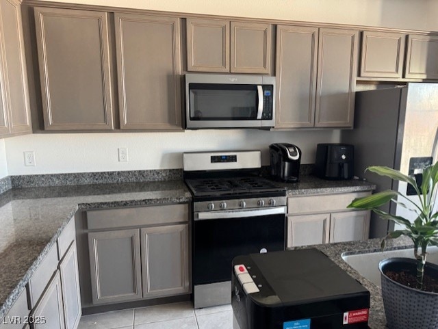 411 Hellebores Ave, North Las Vegas, NV 89084 - kitchen with stainless steel appliances, dark stone counters, and light tile patterned floors