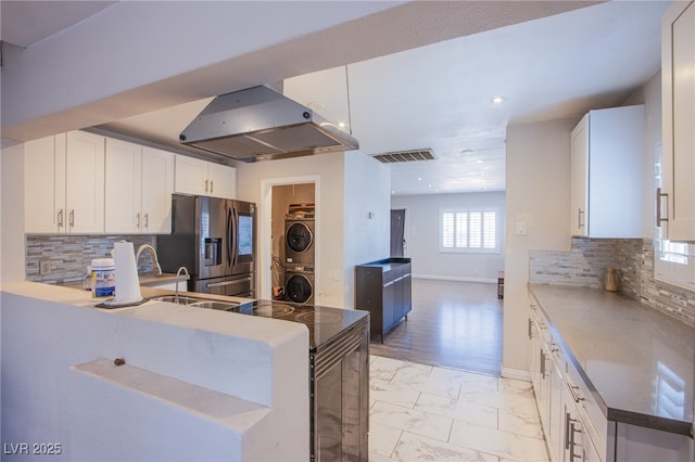 237 Cervantes St, Las Vegas, NV 89101 - kitchen with stacked washer and clothes dryer, extractor fan, stainless steel refrigerator with ice dispenser, light marble finish floors, and backsplash