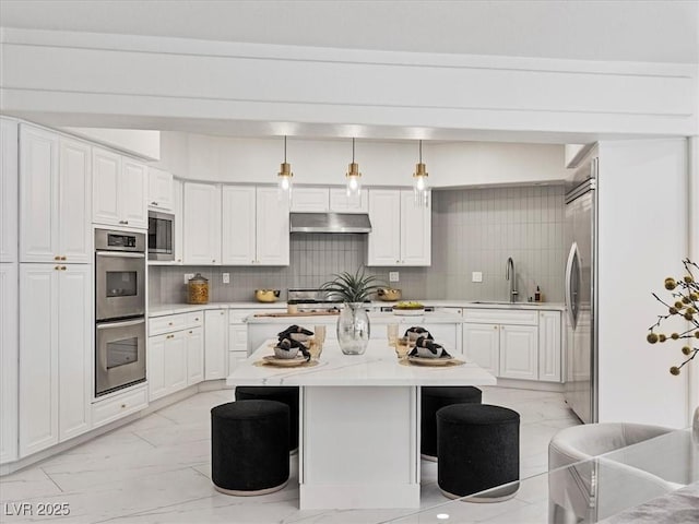 21 Sawgrass Ct, Las Vegas, NV 89113 - kitchen with built in appliances, a sink, light marble finish floors, a center island, and a breakfast bar area