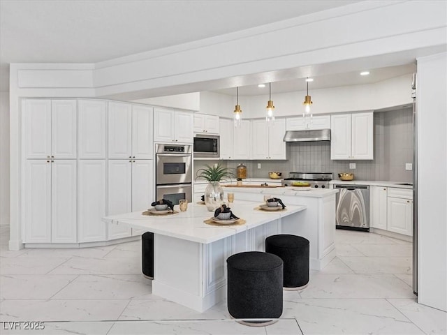 21 Sawgrass Ct, Las Vegas, NV 89113 - kitchen with stainless steel appliances, light marble finish floors, under cabinet range hood, a kitchen island, and a kitchen bar