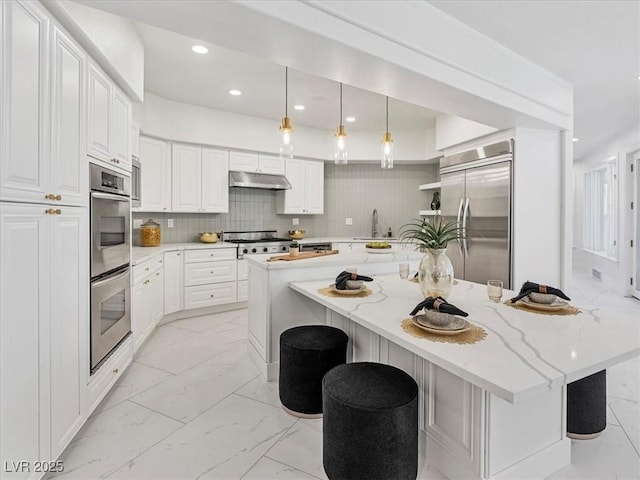 21 Sawgrass Ct, Las Vegas, NV 89113 - kitchen with stainless steel appliances, under cabinet range hood, a sink, a large island, and light marble finish floors