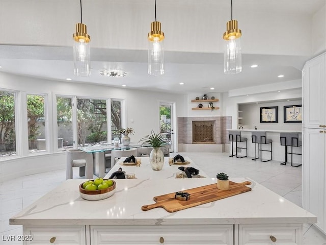 21 Sawgrass Ct, Las Vegas, NV 89113 - kitchen featuring white cabinets, light stone counters, pendant lighting, a fireplace, and recessed lighting