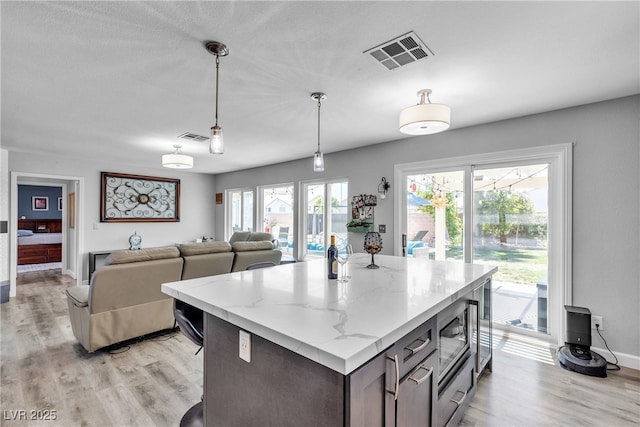 9585 Teton Diablo Ave, Las Vegas, NV 89117 - kitchen featuring light wood-style floors, pendant lighting, stainless steel microwave, baseboards, and a center island