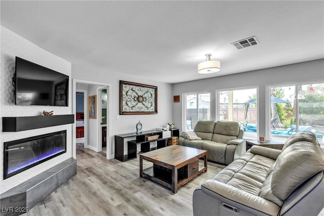 9585 Teton Diablo Ave, Las Vegas, NV 89117 - living room with light wood-style flooring, a glass covered fireplace, baseboards, and a textured ceiling