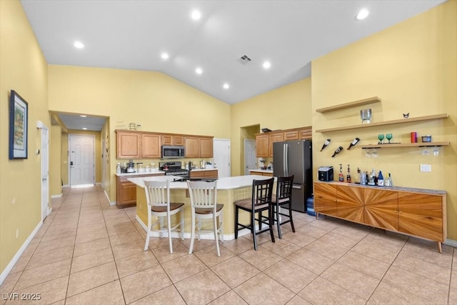 4308 Brazil Palm Ct, North Las Vegas, NV 89032 - kitchen with stainless steel appliances, high vaulted ceiling, light countertops, a spacious island, and a kitchen bar