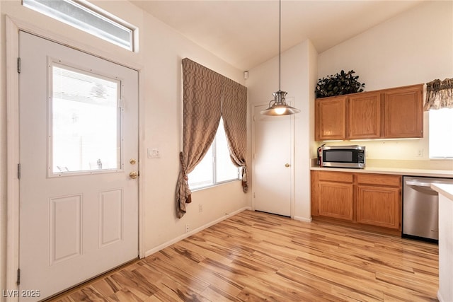 945 Stetson Dr, Henderson, NV 89002 - kitchen featuring stainless steel appliances, light wood finished floors, light countertops, lofted ceiling, and brown cabinets