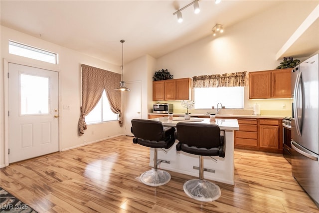945 Stetson Dr, Henderson, NV 89002 - kitchen with stainless steel appliances, light countertops, light wood-style floors, brown cabinets, and high vaulted ceiling