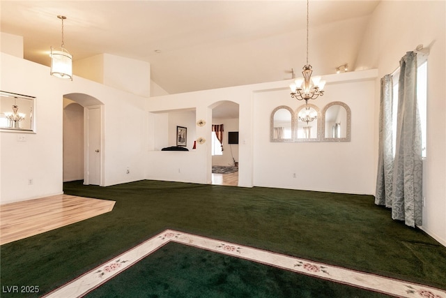 945 Stetson Dr, Henderson, NV 89002 - unfurnished living room featuring carpet floors, a chandelier, arched walkways, and lofted ceiling