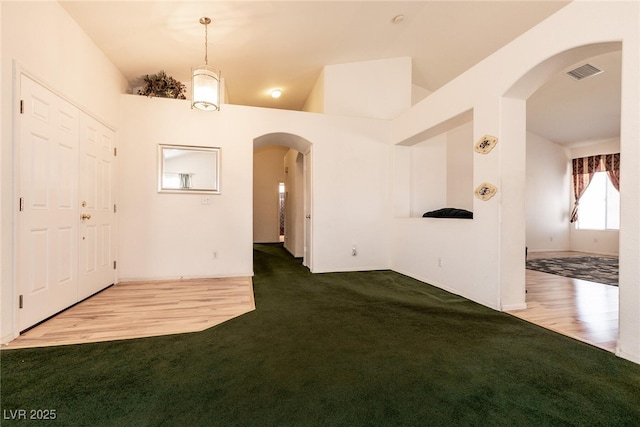 945 Stetson Dr, Henderson, NV 89002 - unfurnished room featuring arched walkways, carpet flooring, wood finished floors, and lofted ceiling