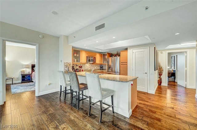 222 Karen Ave Unit 601, Las Vegas, NV 89109 - kitchen with stainless steel appliances, a peninsula, dark wood-style floors, a tray ceiling, and recessed lighting