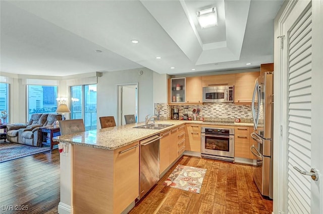 222 Karen Ave Unit 601, Las Vegas, NV 89109 - kitchen featuring appliances with stainless steel finishes, light wood finished floors, a peninsula, a sink, and light stone counters